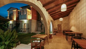 An outdoor dining area with stone walls, wooden tables, and chairs. - Lika Alacati (Cesme)