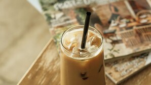 A glass of iced coffee on a wooden table with magazines. - Lika Alacati (Cesme)