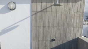 A modern outdoor shower with a textured wall, a wall-mounted light, and a visible drain. - Holiday Home Marina with Mountain View, Terrace & Wi-Fi (Las Palmas de Gran Canaria)
