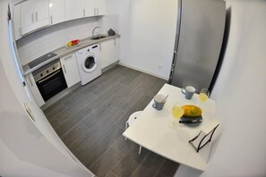 Uma cozinha compacta com máquina de lavar, pia e área de refeições com mesa.