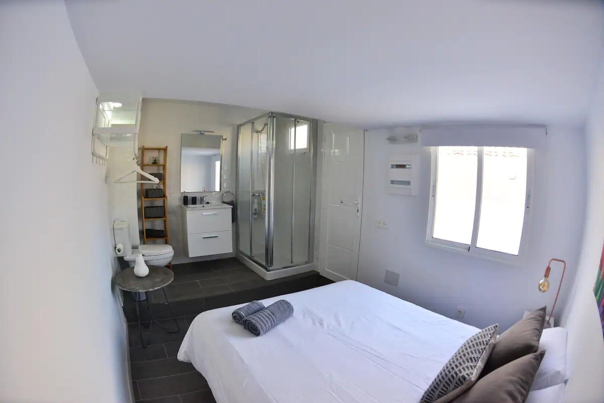 Una camera da letto con un letto, una finestra, una doccia e un bagno con il water e il lavandino.
