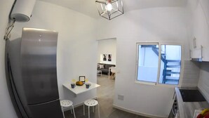 A modern kitchen with a refrigerator, a dining area with a table and chairs, and a window with a view. - Holiday Home Marina with Mountain View, Terrace & Wi-Fi (Las Palmas de Gran Canaria)
