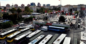 Una stazione degli autobus con diversi autobus parcheggiati, un grande edificio con un cartello e una folla di persone.