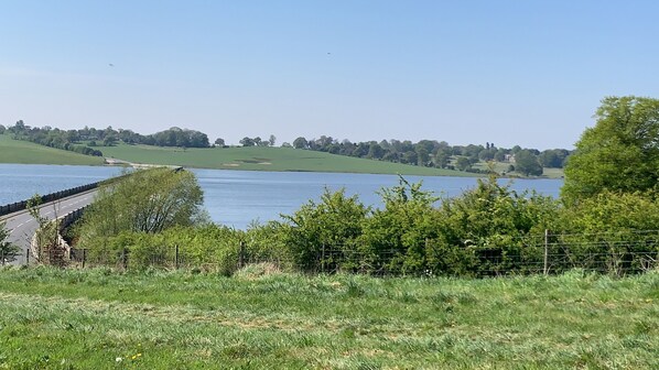 A view of a lake with a road and greenery in the foreground. - Darwen (Rugeley)