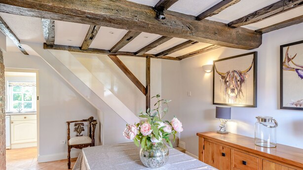 A room with a wooden ceiling, a table with a vase of flowers, a lamp, and a cabinet. - Darwen (Rugeley)