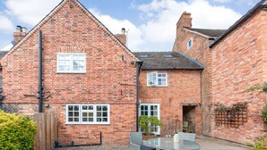 A brick house with a patio, two windows, and a small garden. - Darwen (Rugeley)