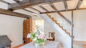 A room with a stone fireplace, a staircase, and a table with a vase of flowers. - Darwen (Rugeley)