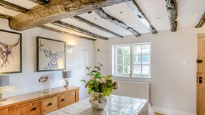A room with a stone table, wooden cabinets, a framed deer painting, a vase with flowers, and a window with a view. - Darwen (Rugeley)