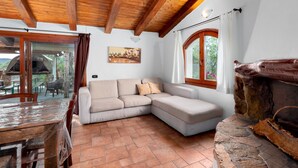 Una habitación acogedora con techo de madera, chimenea de piedra, un sofá y una mesa de comedor.