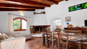 Una sala acogedora con chimenea, una mesa de comedor con sillas, un sofá y un televisor montado en la pared.