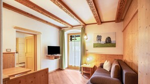 A living room with a wooden ceiling, a sofa, a TV, and a painting on the wall.