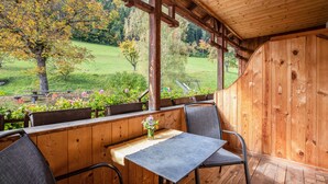 A wooden deck with a table and chairs, overlooking a garden.