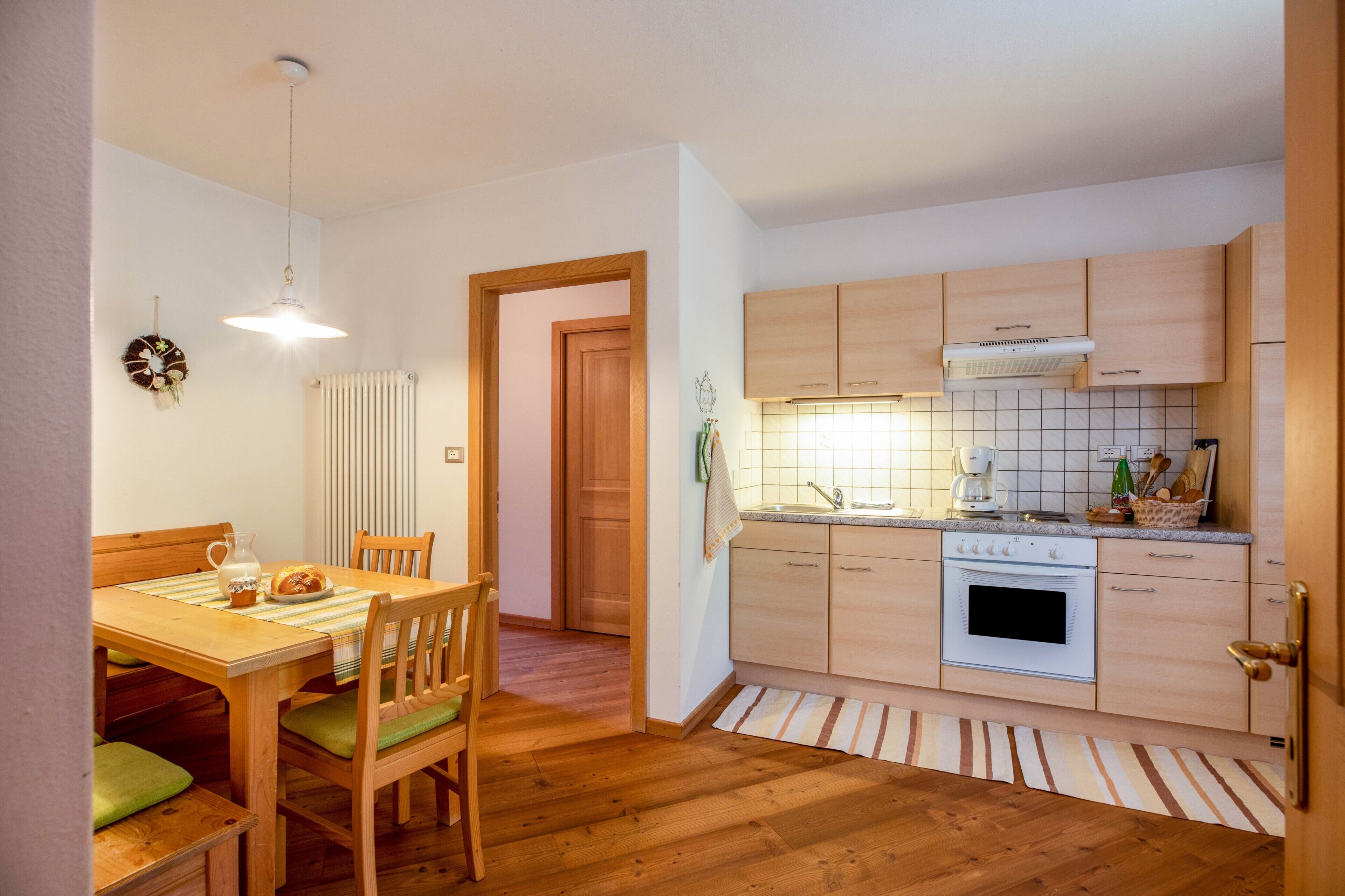 Una cocina con armarios de madera, una estufa y un comedor con mesa y sillas.
