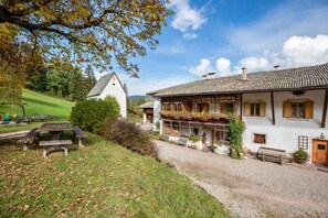 A traditional chalet with a wooden balcony, a gravel driveway, and a picnic area. - 'Apartment Morgenlicht' with Balcony & Wi-Fi (Trodena)
