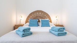 A neatly made bed with blue towels, a woven headboard, and bedside lamps. - Coral Beach by Pat Apartment with Sea Views, Shared Pool, and Wi-Fi (Calafell)