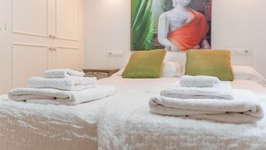 Una habitación de hotel con una cama, dos almohadas, una lámpara de pared y una estatua de Buda.