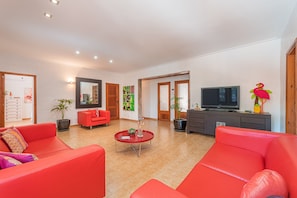 Un salon moderne avec des canapés rouges, un téléviseur à écran plat et une plante en pot.