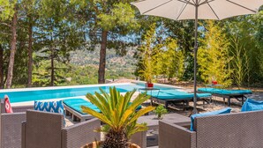 A poolside area with lounge chairs, an umbrella, and a view of the pool and surrounding trees. - Pet-Friendly Villa Ses Basses with Mountain View, Pool & Wi-Fi (mancor de la vall)