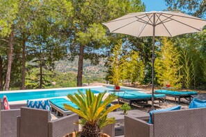 A poolside area with lounge chairs, an umbrella, and a view of the pool and surrounding trees. - Pet-Friendly Villa Ses Basses with Mountain View, Pool & Wi-Fi (mancor de la vall)