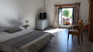 A bedroom with a bed, a television on a dresser, a chair, and a balcony with curtains. - Gîte for 2 to 6 people: relaxation and easy living (Phalsbourg)