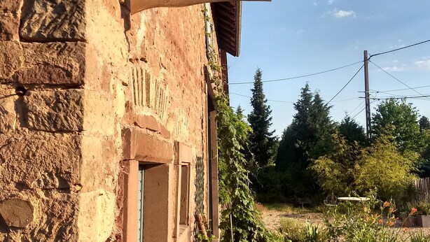 A rustic stone building with a wooden signboard displaying the name and contact information. - Gîte for 2 to 6 people: relaxation and easy living (Phalsbourg)