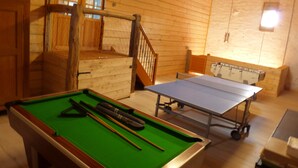 A pool table with billiard cues and a ping pong table in a wooden room with a staircase and a sofa. - Gîte for 2 to 6 people: relaxation and easy living (Phalsbourg)