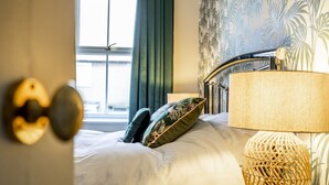 A hotel room with a bed, a lamp, and a view of the outside.