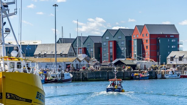 A harbor with boats, a yellow ship named 'NIMROD', and colorful buildings.