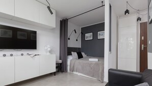 A modern, compact living space with a bed, a sofa, a TV, and a desk. - Stylish Studio in Mokotow | Balcony | Close to Metro (Warszawa)