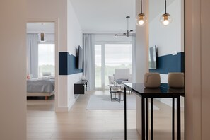Et moderne hotelværelse med seng, skrivebord, stol, fjernsyn og stort vindue.