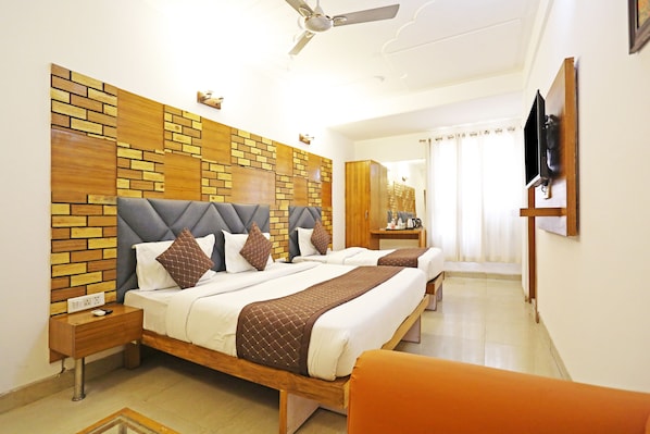 A hotel room with two beds, a wooden headboard, a ceiling fan, a TV, and a bathroom visible through a door.