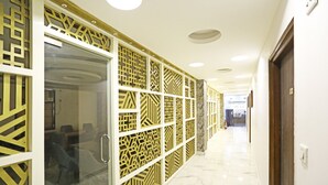 A hallway with a patterned wall and a glass door leading to a room. - MyHomeHotels – Hotel Ambrosia (New Delhi)
