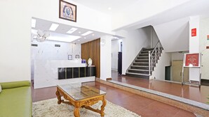 A reception area with a reception desk, a staircase, and a green sofa. - MyHomeHotels – Hotel Ambrosia (New Delhi)