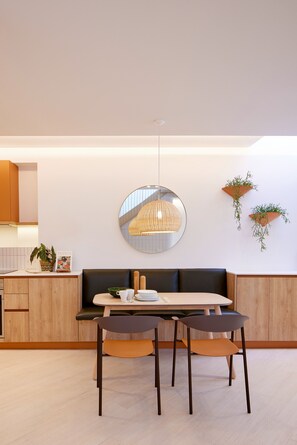 Een moderne eethoek met een ronde spiegel, houten meubels en hangplanten.