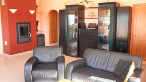A living room with a fireplace, two black leather sofas, and a glass cabinet with shelves.