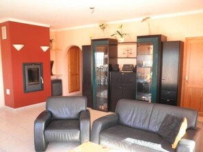 Una sala de estar con chimenea, dos sofás de cuero negro y un aparador de vidrio con estantes.