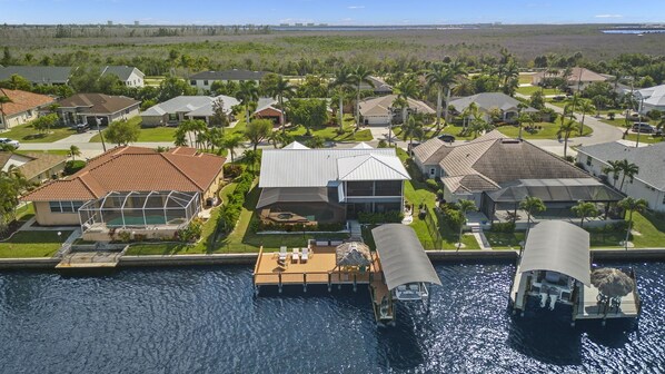 A residential area with houses, a swimming pool, and a dock with boats. - Gulf Access ☀️6BR ☀️Heated Pool ☀️Spa☀️Dock ☀️Tiki Hut ☀️Sleeps 11 (Cape Coral)