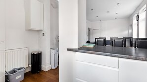 Una cucina moderna con mobili bianchi, un piano di lavoro grigio e un cestino nero.