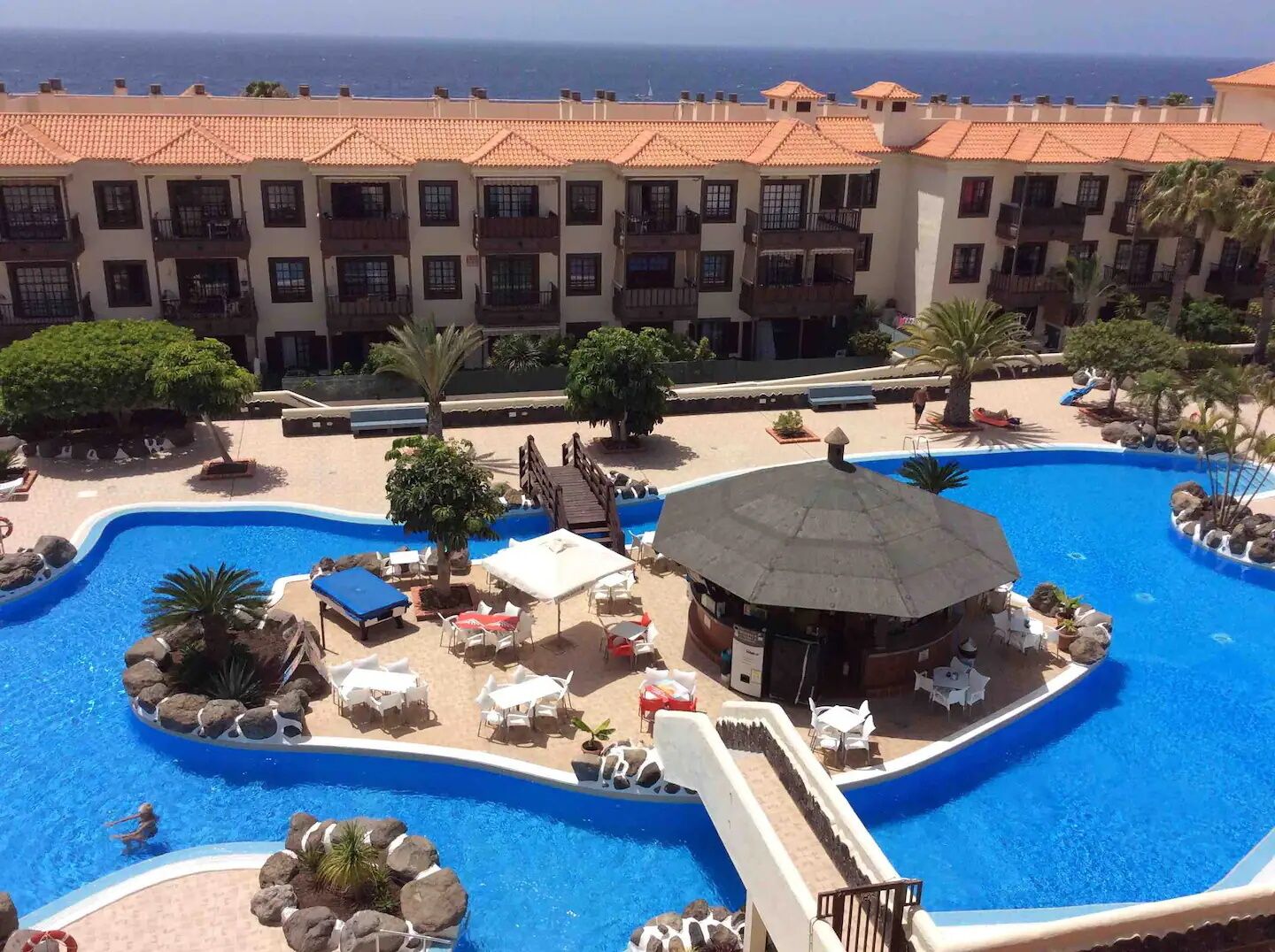 A resort with a large pool, lounge chairs, and a view of the ocean.