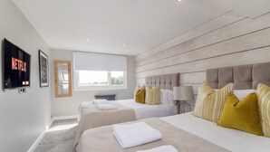 Habitación de hotel con dos camas, televisión, ventana y techo de madera.