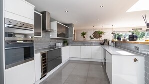 Una cocina moderna con electrodomésticos integrados, armarios blancos y salpicadero de azulejos.