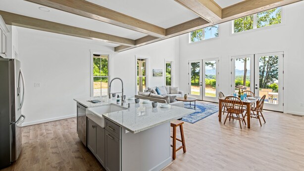 Un'ampia cucina con una grande isola, travi in legno e vista su un vigneto attraverso le porte scorrevoli in vetro.