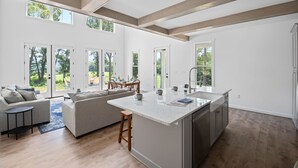 Un'ampia cucina con un'isola grande, travi in legno e ampie finestre che offrono vista sull'esterno.