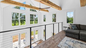 Un'ampia zona giorno con soffitto alto, ampie finestre e un balcone.