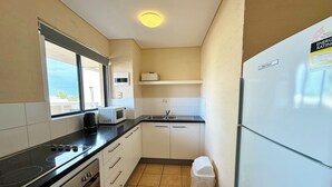 Une cuisine de taille réduite équipée d’une cuisinière, d’un four à micro-ondes, d’un évier et d’un réfrigérateur.