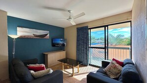 Un salon avec un téléviseur, un canapé et un ventilateur de plafond.