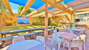 An outdoor patio with tables and chairs, a mural, and a barbecue area.