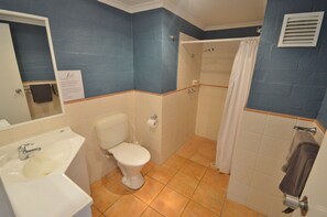 A bathroom with a toilet, sink, shower, and a towel rack.
