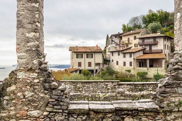 Un mur de pierre offrant une vue sur des bâtiments traditionnels et, au loin, sur une étendue d’eau.