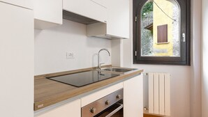 Une cuisine moderne équipée d’une cuisinière intégrée, d’un évier et d’une fenêtre donnant sur un immeuble jaune.